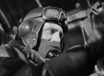 Movie still from “One of Our Aircraft Is Missing” (1942), directed by Emeric Pressburger – A man wearing a helmet and goggles in the dark; Medium shot, Low angle