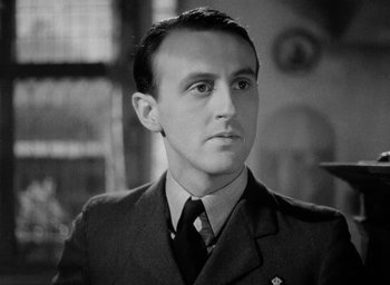 Movie still from “One of Our Aircraft Is Missing” (1942), directed by Emeric Pressburger – Black and white photograph of a man in a uniform; Close Up shot, Low angle