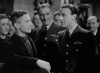 Movie still from “One of Our Aircraft Is Missing” (1942), directed by Emeric Pressburger – A black and white photo of two men shaking hands; Medium shot, Low angle