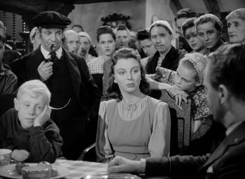 Movie still from “One of Our Aircraft Is Missing” (1942), directed by Emeric Pressburger – A group of people sitting around a table; Medium shot, Over the shoulder angle