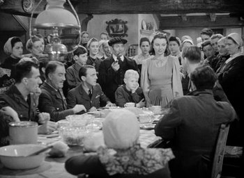 Movie still from “One of Our Aircraft Is Missing” (1942), directed by Emeric Pressburger – A group of people sitting around a dinner table; Medium shot, High angle