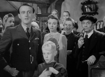 Movie still from “One of Our Aircraft Is Missing” (1942), directed by Emeric Pressburger – A black and white photo of a group of people; Medium shot, Low angle