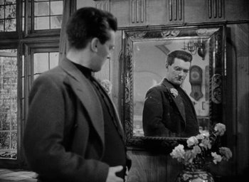 Movie still from “One of Our Aircraft Is Missing” (1942), directed by Emeric Pressburger – A man standing in front of a mirror looking at himself in the mirror; Close Up shot, Over the shoulder angle