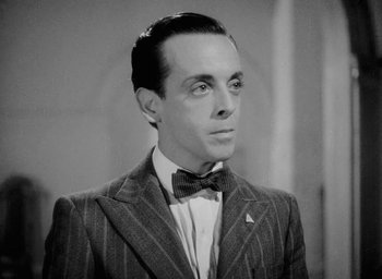Movie still from “One of Our Aircraft Is Missing” (1942), directed by Emeric Pressburger – A man wearing a suit and bow tie; Close Up shot, Low angle