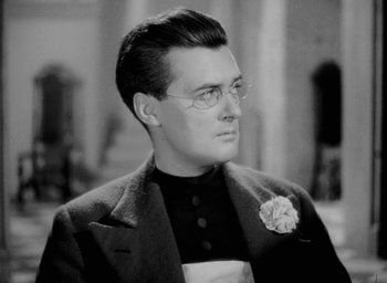 Movie still from “One of Our Aircraft Is Missing” (1942), directed by Emeric Pressburger – A man in a suit with a flower in his hair; Close Up shot, Low angle