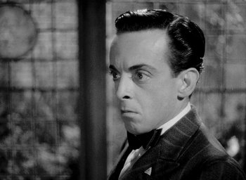 Movie still from “One of Our Aircraft Is Missing” (1942), directed by Emeric Pressburger – An old photo of a man in a suit and tie; Close Up shot, Low angle