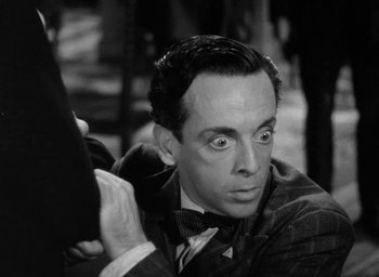 Movie still from “One of Our Aircraft Is Missing” (1942), directed by Emeric Pressburger – An old photo of a man with a surprised look on his face; Close Up shot, High angle