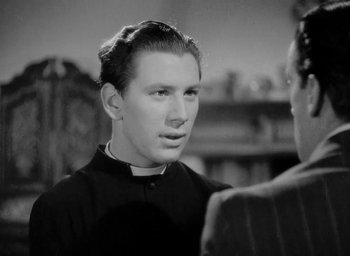 Movie still from “One of Our Aircraft Is Missing” (1942), directed by Emeric Pressburger – A young man wearing a priest's outfit talking to another man; Close Up shot, Over the shoulder angle