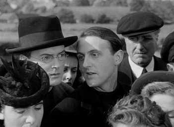 Movie still from “One of Our Aircraft Is Missing” (1942), directed by Emeric Pressburger – A group of people standing next to each other in a field; Close Up shot, Over the shoulder angle