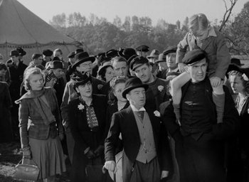 Movie still from “One of Our Aircraft Is Missing” (1942), directed by Emeric Pressburger – A group of men and women wearing hats and ties; Medium shot, High angle