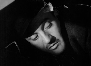 Movie still from “One of Our Aircraft Is Missing” (1942), directed by Emeric Pressburger – A black and white photo of a man in a hat; Close Up shot, High angle