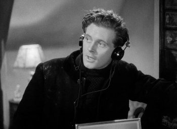 Movie still from “One of Our Aircraft Is Missing” (1942), directed by Emeric Pressburger – A black and white photo of a man wearing headphones; Close Up shot, High angle