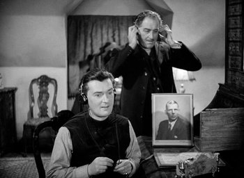 Movie still from “One of Our Aircraft Is Missing” (1942), directed by Emeric Pressburger – Two men are sitting in a living room; Medium shot, High angle