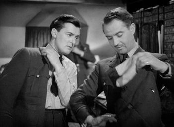 Movie still from “One of Our Aircraft Is Missing” (1942), directed by Emeric Pressburger – Two men in suits and ties are looking at each other's neckties; Medium shot, Low angle