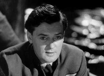 Movie still from “One of Our Aircraft Is Missing” (1942), directed by Emeric Pressburger – Black and white photograph of a man in a suit and tie; Close Up shot, Low angle