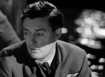 Movie still from “One of Our Aircraft Is Missing” (1942), directed by Emeric Pressburger – Black and white photograph of a man in a suit and tie; Close Up shot, Low angle