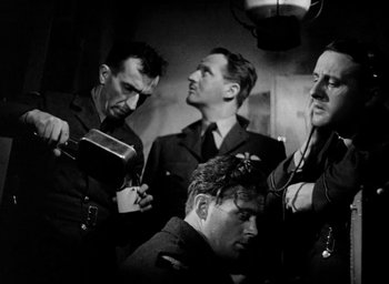 Movie still from “One of Our Aircraft Is Missing” (1942), directed by Emeric Pressburger – A black and white photo of a group of men; Medium shot, Low angle