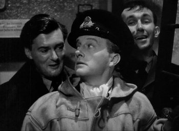 Movie still from “One of Our Aircraft Is Missing” (1942), directed by Emeric Pressburger – A man in a uniform with two other men in the background; Medium shot, High angle