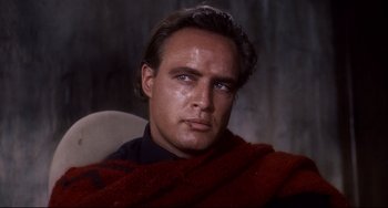 Movie still from “One-Eyed Jacks” (1961), directed by Marlon Brando – A person wearing a red blanket; Close Up shot, Low angle