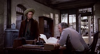 Movie still from “One-Eyed Jacks” (1961), directed by Marlon Brando – Two men sitting at a table looking at papers; Medium shot, Over the shoulder angle