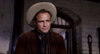 Movie still from “One-Eyed Jacks” (1961), directed by Marlon Brando – A man wearing a cowboy hat and a brown jacket; Close Up shot, Low angle