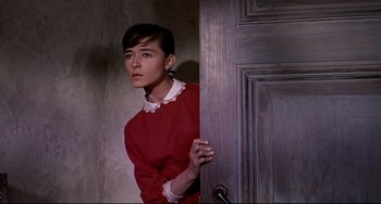 A woman in a red shirt standing in front of a door