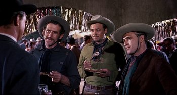 Movie still from “One-Eyed Jacks” (1961), directed by Marlon Brando – A group of men standing next to each other holding food; Medium shot, Low angle