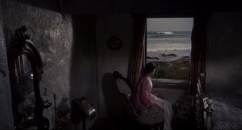 Movie still from “One-Eyed Jacks” (1961), directed by Marlon Brando – A woman sitting in a chair looking out a window at the ocean; Extreme Wide shot, High angle