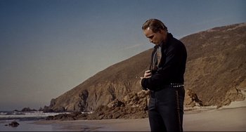 Movie still from “One-Eyed Jacks” (1961), directed by Marlon Brando – A man standing on the beach looking at his watch; Medium shot, Low angle
