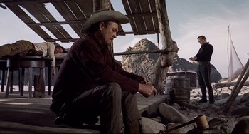 Movie still from “One-Eyed Jacks” (1961), directed by Marlon Brando – A man in a cowboy hat sitting on a bench; Medium shot, Low angle
