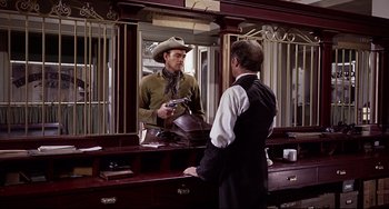 Movie still from “One-Eyed Jacks” (1961), directed by Marlon Brando – A man in a cowboy hat is standing in front of a man in a suit; Medium shot, Over the shoulder angle