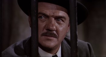 Movie still from “One-Eyed Jacks” (1961), directed by Marlon Brando – A person behind bars wearing a suit and hat; Close Up shot, Low angle