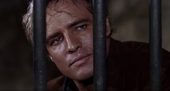 Movie still from “One-Eyed Jacks” (1961), directed by Marlon Brando – A person behind a metal fence; Close Up shot, Low angle
