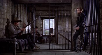Movie still from “One-Eyed Jacks” (1961), directed by Marlon Brando – A group of people sitting in a room with bars around them; Wide shot, Low angle