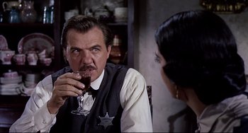 Movie still from “One-Eyed Jacks” (1961), directed by Marlon Brando – A man drinking a glass of wine in front of a woman; Close Up shot, Over the shoulder angle