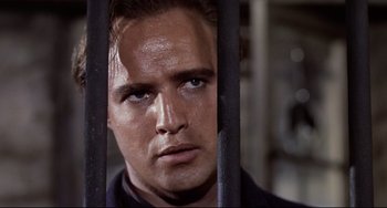 Movie still from “One-Eyed Jacks” (1961), directed by Marlon Brando – A person behind a metal fence; Close Up shot, Low angle