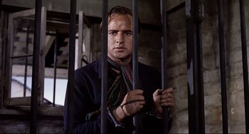 Movie still from “One-Eyed Jacks” (1961), directed by Marlon Brando – A man in a black jacket is holding a jail cell; Close Up shot, Low angle
