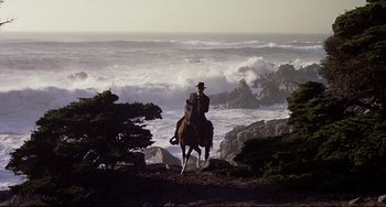 Movie still from “One-Eyed Jacks” (1961), directed by Marlon Brando – A man riding a horse on top of a hill near the ocean; Wide shot, Low angle