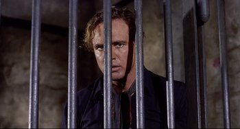 Movie still from “One-Eyed Jacks” (1961), directed by Marlon Brando – A man standing behind bars in a jail cell; Close Up shot, Low angle