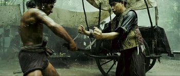 Movie still from “Ong Bak 2” (2008), directed by Tony Jaa – Two men are fighting in the middle of the rain; Medium shot, Over the shoulder angle