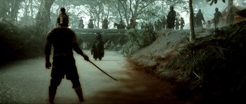 Movie still from “Ong Bak 2” (2008), directed by Tony Jaa – A group of people standing on top of a dirt road; Wide shot, High angle