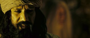 Movie still from “Ong Bak 2” (2008), directed by Tony Jaa – A man with long black hair wearing a turban; Close Up shot, Over the shoulder angle
