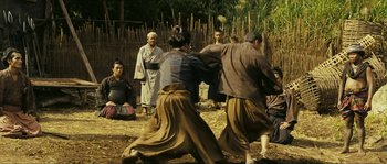 Movie still from “Ong Bak 2” (2008), directed by Tony Jaa – A group of people standing in a field; Wide shot, Low angle
