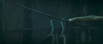 Movie still from “Ong Bak 2” (2008), directed by Tony Jaa – A person holding a sword in the rain; Close Up shot, Low angle