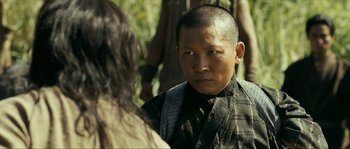 Movie still from “Ong Bak 2” (2008), directed by Tony Jaa – A man with a shaved head is talking to a woman; Close Up shot, Over the shoulder angle