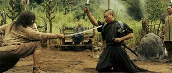 Movie still from “Ong Bak 2” (2008), directed by Tony Jaa – A man holding a sword in front of another man; Medium shot, Over the shoulder angle