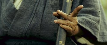 Movie still from “Ong Bak 2” (2008), directed by Tony Jaa – A person holding a stick in their hand; Extreme Close Up shot, Low angle