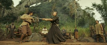Movie still from “Ong Bak 2” (2008), directed by Tony Jaa – Two people are practicing martial arts in the woods; Wide shot, Low angle