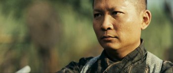 Movie still from “Ong Bak 2” (2008), directed by Tony Jaa – A person wearing a camouflage shirt; Close Up shot, Low angle