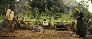 Movie still from “Ong Bak 2” (2008), directed by Tony Jaa – Two men sitting on a bench in the middle of a field; Wide shot, High angle